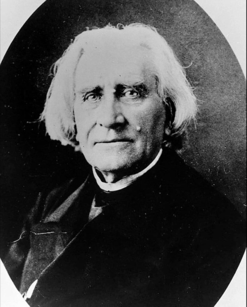 Photo in black and white taken in 1882. It represents Liszt facing the camera, slightly smiling. He is wearing a cassock. We can see his shoulders and his head.