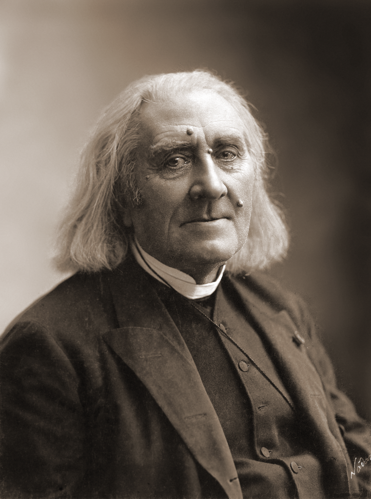 Picture in black and white taken in 1886. It represents Liszt wearing a black cassock and a black coat, facing the camera and smiling. 