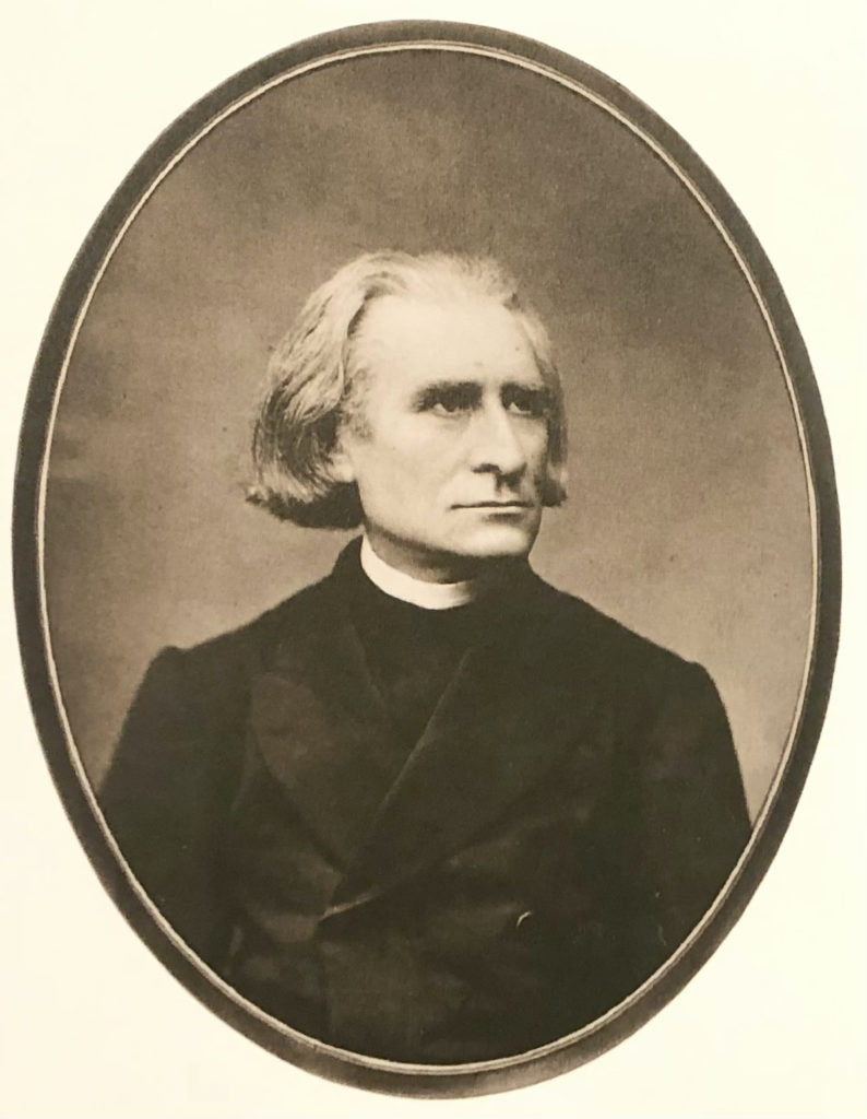 Picture in black and white taken in 1871. It represents Liszt wearing a black cassock and a black coat. He looks toward his left.