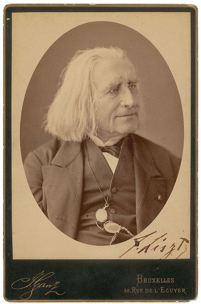 Picture in black and white taken in 1881. It represents Liszt with a black vest, looking toward his left, smiling. His glasses are attached to a string tightened around his neck. The photo is signed by Liszt. At the bottom, the name of the photographer and his address.