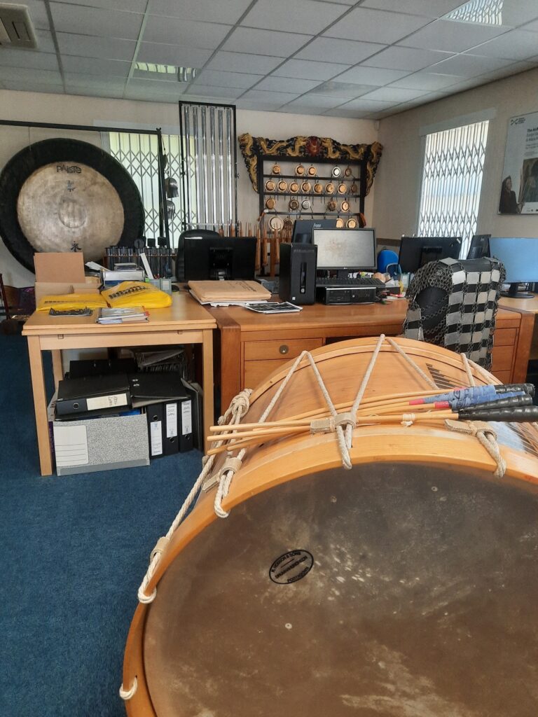 A giant drum at the front, several desks, and other percussions in the back.