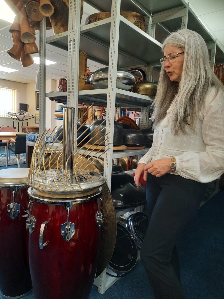 Evelyn shows an instrument called the Waterphone, a round instrument with twisted metallic tubes.