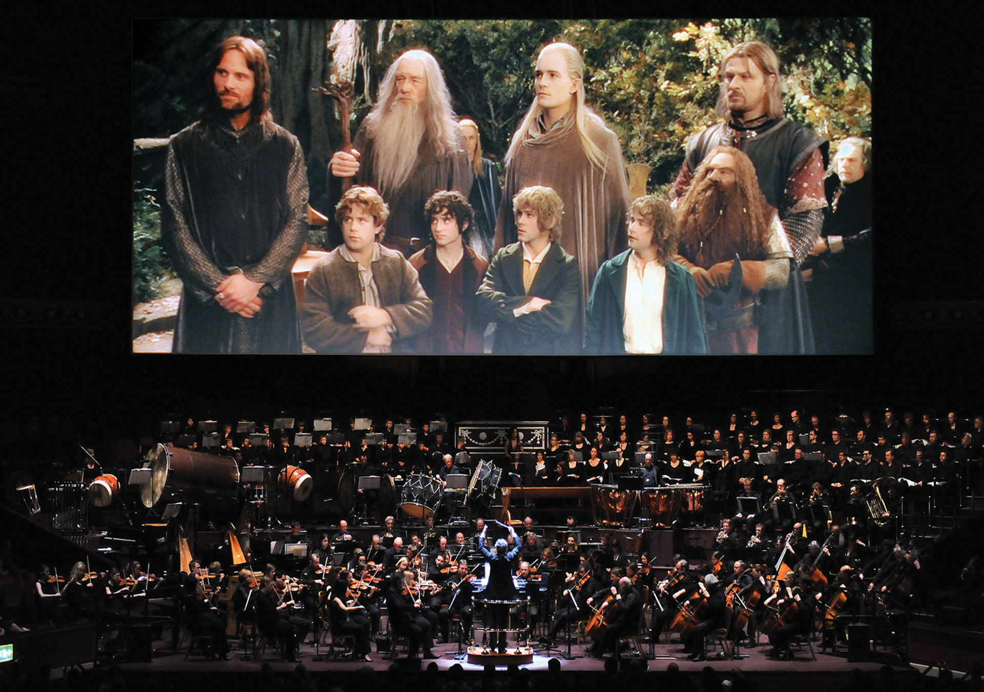 Picture of the movie Lord of the Rings projected on a gigantic screen, with a full orchestra and choir performing the music under the screen.
